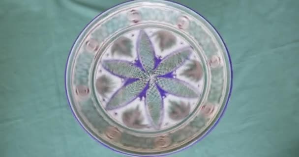 ラグの背景に陶芸家のスタジオでパターンで描かれた完成した磁器プレートの回転 リアルタイム4K — ストック動画