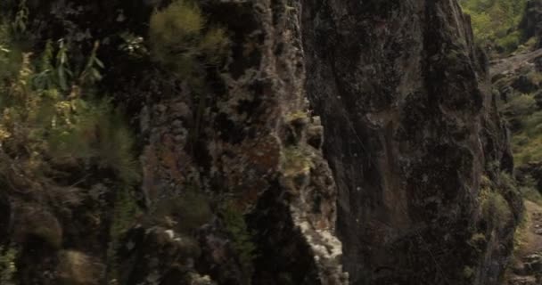 急な崖の上にあるベレー帽の上に 若い運動選手の女性登山家の周りをドローンが飛んでいます 空中展望 — ストック動画