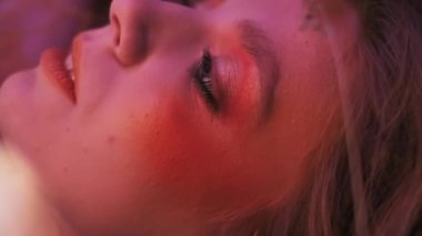 Dallardan, yapraklardan ve mısır başaklarından oluşan sonbahar kıyafeti içindeki genç bir kadının dağınık elmaların arasında çimlerin üzerinde uçarken makro görüntüsü. Yavaş Hareket.