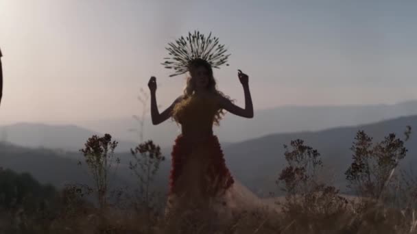秋の花や草の衣装の若い女性とトウモロコシの耳で作られたヘッドドレスは 山の夕日を背景に立っています スローモーション — ストック動画