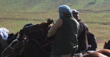 Bir grup atlı, tepelerdeki sarı sonbahar otlarının arasında dörtnala koşuyor. Orta Asya, Yavaş Hareket, Yakın Çekim.