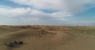 Dronn bulutlu bir günde çölün kum tepelerinin üzerinden uçar. Hava görünümü