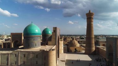Özbekistan 'ın eski Buhara kentindeki Poi-Kalon mimari kompleksinin kapısındaki bir grup turistin üzerinde bir dron uçuyor. Bulutlu bir gün. Hava Görünümü.