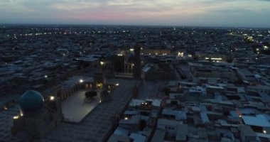 Özbekistan 'ın Buhara kentindeki eski evler arasında Poi-Kalon mimari kompleksinin üzerinde bir dron uçuyor. Bulutlu bir gece. Hava Görünümü.