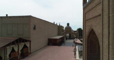 Özbekistan 'ın Buhara kentindeki eski evlerle çevrili Magok-i-Attari Cami kompleksinin üzerinde bir İHA uçuyor. Bulutlu bir gün. Hava Görünümü.