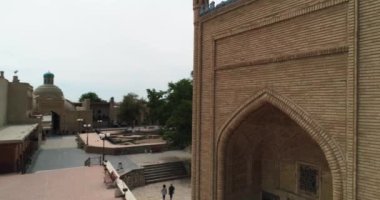 İnsansız hava aracı Özbekistan 'ın eski Buhara kentindeki Magok-i-Attari Cami kompleksinin ana kapısına yakın uçuyor. Bulutlu bir gün. Hava Görünümü.