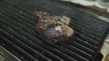 Şef ızgara bifteğe dokunur ve onu çevirir. Yavaş Hareket, Kapat.