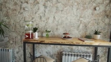 Küçük, rahat bir otelin resepsiyonu ve lobisi. Kimse yok.