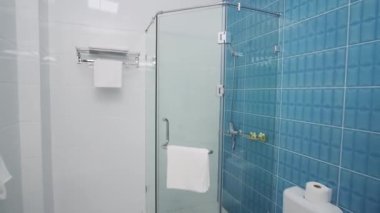 Küçük, rahat bir otelin duş kabininde. Lavabo, tuvalet, havlu, bornoz..