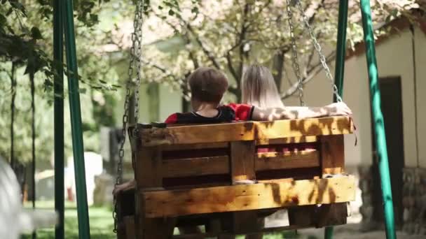 一位成年母亲带着一个年幼的女儿在她家旁边的花园里荡秋千 说话和笑 慢动作 — 图库视频影像
