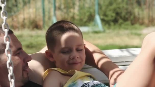 Teenager Lies Top His Young Father Swing Park Sunny Day — Stock Video