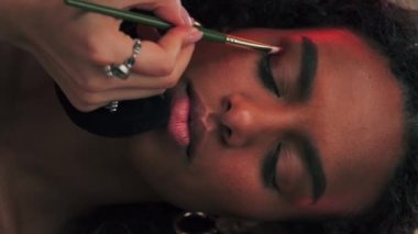 Göz kapaklarını boyayan genç esmer bir kadının yüzünü yakından çek. Yavaş Hareket.