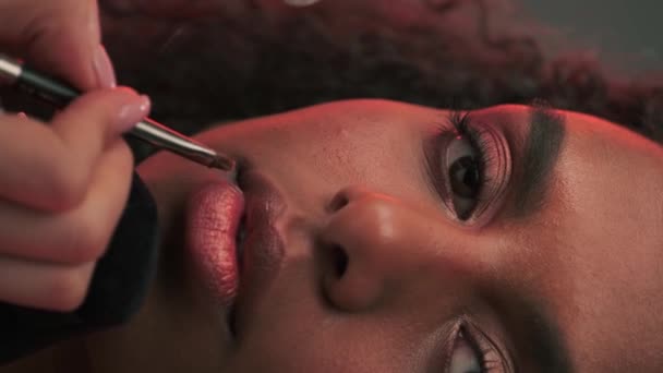 写真スタジオで若い魅力的なモデルの唇に口紅を塗ったメイクアップアーティスト スローモーション — ストック動画