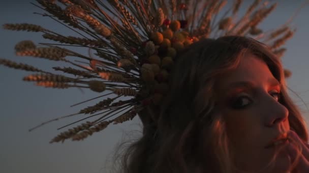 山の夕日を背景に秋のヘッドドレスで若い女性のクローズアップ顔 スローモーション — ストック動画
