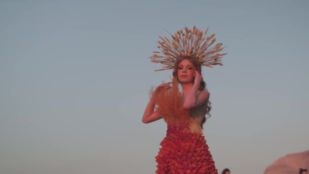 秋のデザイナーズドレスで若い女性モデルと 山の夕日を背景にスパイシーツで作られたヘッドドレス スローモーション — ストック動画