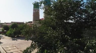 İnsansız hava aracı Chor Minor 'un yakınındaki bir ağacın yanından geçiyor. Khalif Niyaz-kul' un Madrasah 'ı. Eski Buhara, Özbekistan. Güneşli bir gün. Hava Görünümü.