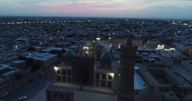 Özbekistan 'ın Buhara kentindeki eski evler arasında Poi-Kalon mimari kompleksinin üzerinde bir dron uçuyor. Bulutlu bir gece. Hava Görünümü.