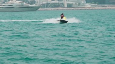 Açık denizlerde jet ski üzerinde can yeleği giymiş esmer bir kadın. Yavaş çekim