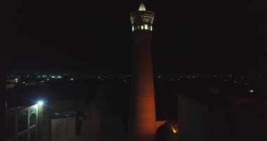 Karmaşık Kalyan Minaresi 'nin aydınlatılmış antik kulesinin yakınında bir dron gece uçar. Buhara, Özbekistan, Havadan görünüm.