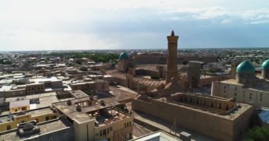 Güneşli ve bulutlu bir günde antik bir Kalyan Minaresi 'nin kulesinin üzerinde bir dron uçuyor. Eski Buhara, Özbekistan. Hava Görünümü.