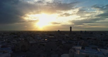Bir dron, günbatımı gökyüzünün arka planında antik bir Lyab-i Hauz kompleksinin üzerinden uçuyor. Eski Buhara, Özbekistan civarında. Hava Görünümü.