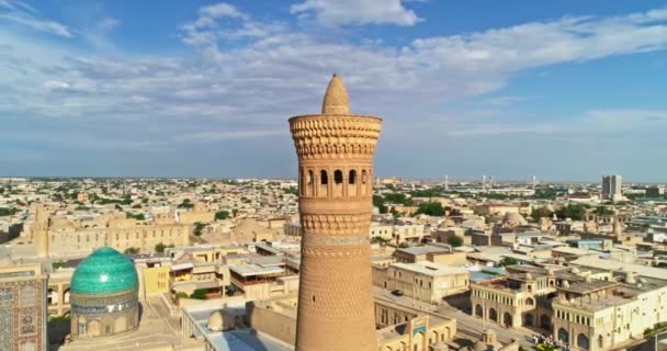 ドローンは古代の複雑なカリアン ミナレットの塔の周りを曇った晴れた日に飛ぶ オールド ブハラ ウズベキスタン エアリアルビュー — ストック動画