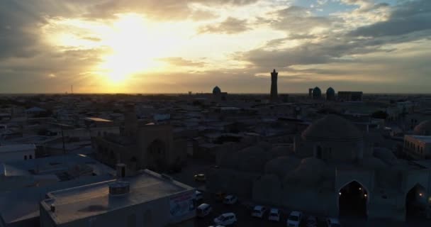 无人驾驶飞机与成群的游客一起飞越了Kalyan Minaret建筑群的古塔 关于乌兹别克斯坦布哈拉老城区背景的命令 空中视图 — 图库视频影像