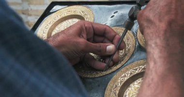 Usta bir kabartma makinesi eski teknolojileri kullanarak bakır plaka üzerinde bir kalıp oluşturur. Buhara, Özbekistan.