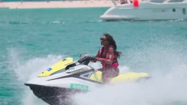 Açık denizlerde jet ski üzerinde can yeleği giymiş esmer bir kadın. Yavaş çekim