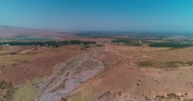 Bir dron dağların ve tepelerin arasında kurumuş bir nehrin üzerinde uçuyor. Hava görüntüsü, yavaş çekim