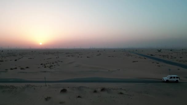 無人機は砂漠の砂の間の空の道を運転する2台の高価な車によって飛ぶ 空中ビュー スローモーション — ストック動画
