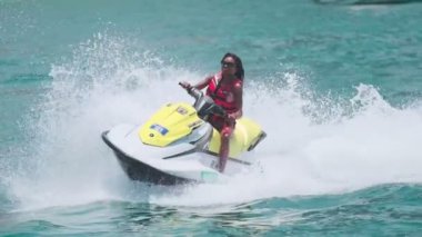 Açık denizlerde jet ski üzerinde can yeleği giymiş esmer bir kadın. Yavaş çekim