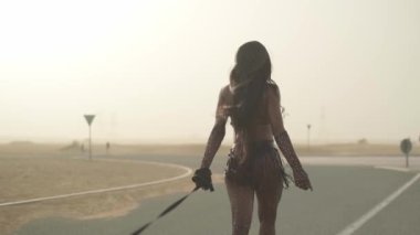 Seksi kıyafetli genç esmer kadın çölde yolda pahalı bir spor arabaya liderlik ediyor. Yavaş Hareket.