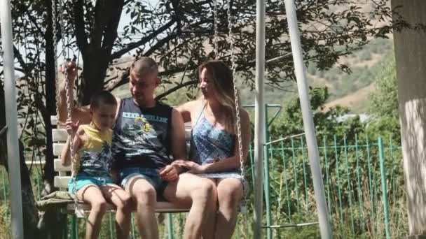 Família Pai Mãe Filho Balançando Balanço Parque Dia Ensolarado Abraçam — Vídeo de Stock