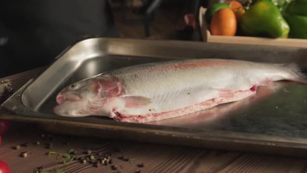 Chef Handskar Salta Fisk Köksbordet Bland Örter Tomater Och Grönsaker — Stockvideo