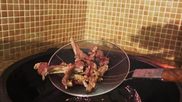 Der Koch Holt Mit Einem Schlitzlöffel Fleischstücke Aus Dem Einem — Stockvideo