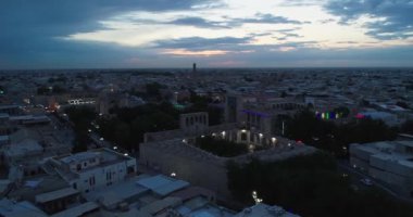 Eski Buhara, Özbekistan 'daki evlerle çevrili antik bir Lyab-i Hauz kompleksinin üzerinde bir İHA uçuyor. Bulutlu bir gece. Hava Görünümü.