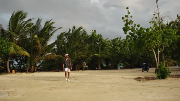 Açık Renk Elbiseli Genç Bir Adam Tropik Palmiye Ağaçlarıyla Çevrili — Stok video