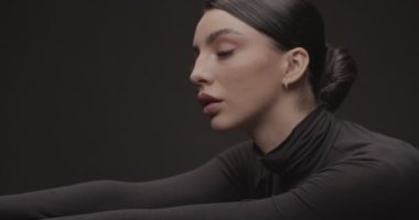 Stüdyoda siyah arka planda genç bir kadının portresi çekiliyor. Yavaş Hareket.