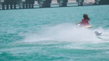 Açık denizlerde jet ski üzerinde can yeleği giymiş esmer bir kadın. Yavaş çekim