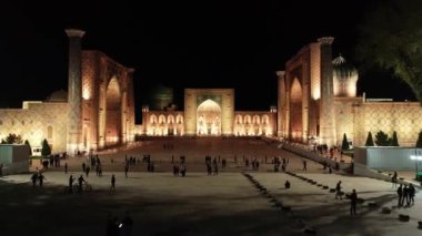 Aydınlanmış Registan kompleksinin insansız hava aracı panoraması, Semerkant, Özbekistan. Hava Görünümü, Yavaş Hareket.