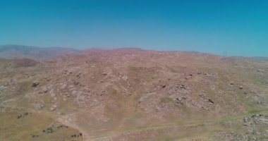 İnsansız hava aracı bulutsuz bir günde dağlarla çevrili kayalık tepelerin üzerinden uçar. Hava Görünümü, Yavaş Hareket