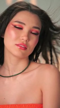 Rüzgarda savrulan uzun saçlı ve parlak makyajlı genç bir kadının dikey portresi. Yavaş Çekim, Kapat, Stüdyo Çekimi.