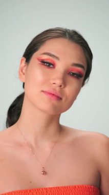 Uzun siyah saçlı ve parlak makyajlı genç bir mankenin dikey portresi. Yavaş Çekim, Kapat, Stüdyo Çekimi.