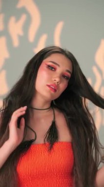 Uzun siyah saçlı ve parlak makyajlı genç bir mankenin dikey portresi. Yavaş Çekim, Kapat, Stüdyo Çekimi.