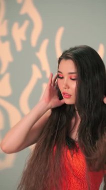 Uzun siyah saçlı ve parlak makyajlı genç bir mankenin dikey portresi. Yavaş Çekim, Kapat, Stüdyo Çekimi.