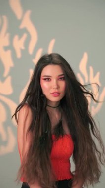 Uzun siyah saçlı ve parlak makyajlı genç bir mankenin dikey portresi. Yavaş Çekim, Kapat, Stüdyo Çekimi.