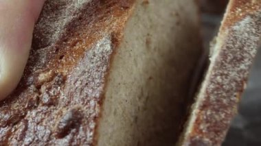 Taze fırınlanmış buğday ekmeğini yakın plan kesiyorum. Çerçevede bir erkek eli.