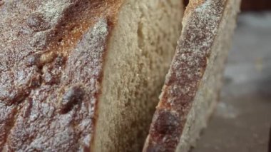 Taze fırınlanmış buğday ekmeğini yakın plan kesiyorum. Çerçevede bir erkek eli.