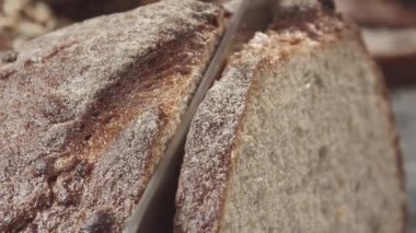 Taze fırınlanmış buğday ekmeğini yakın plan kesiyorum. Çerçevede bir erkek eli.